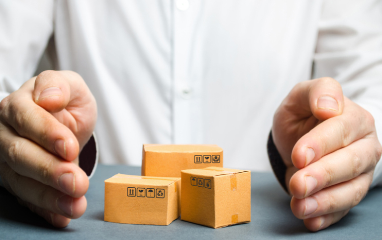 A man covers his hands with cardboard boxes or goods. The concept of saving the safety and integrity of parcels and goods. Shipping insurance. Retail services, sales and storage in a warehouse.