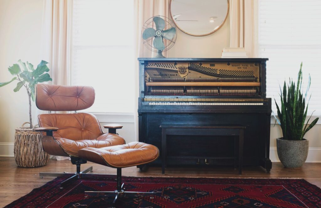 Black upright piano near a brown leather padded chair