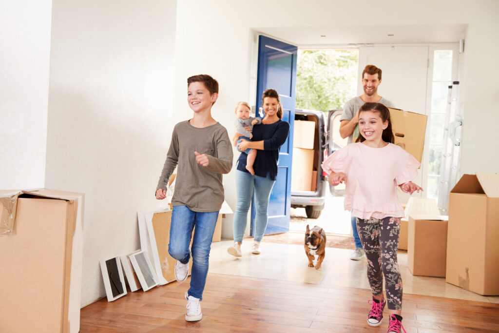 Family Carrying Boxes Into New Home On Moving Day