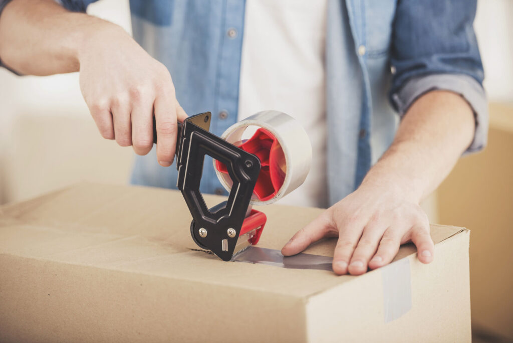 Young man packing and labelling a moving box