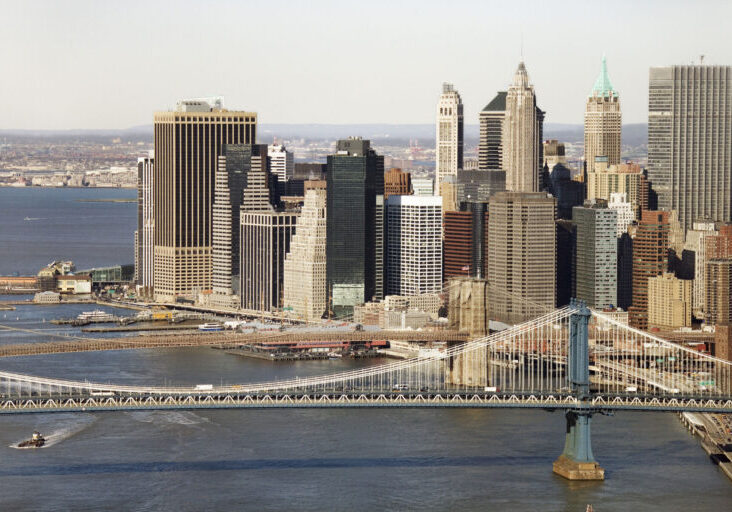 Aerial view of New York City's Manhattan Bridge with Brooklyn Bridge and Manhattan buildings in background.