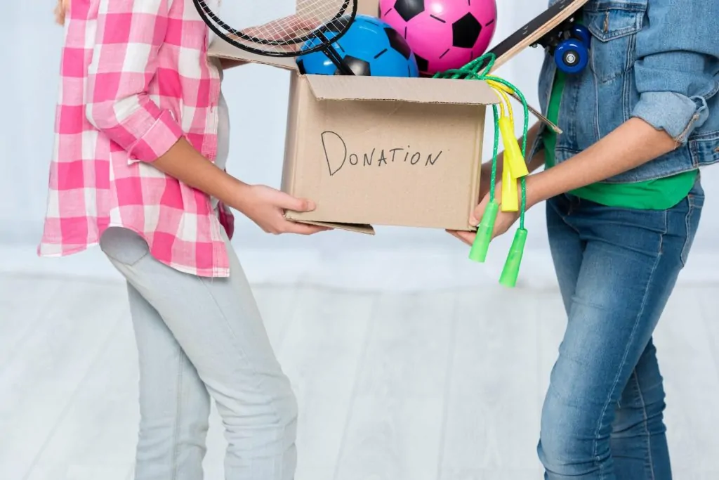 People holding a donations box with clothes, representing where to donate items in NYC