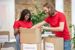 Couple packing a donations box before moving, showing where to donate items before relocating.
