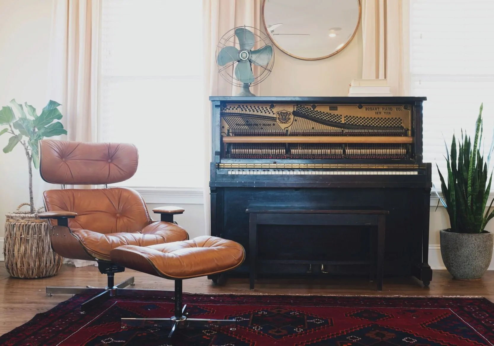 Black upright piano near a brown leather padded chair